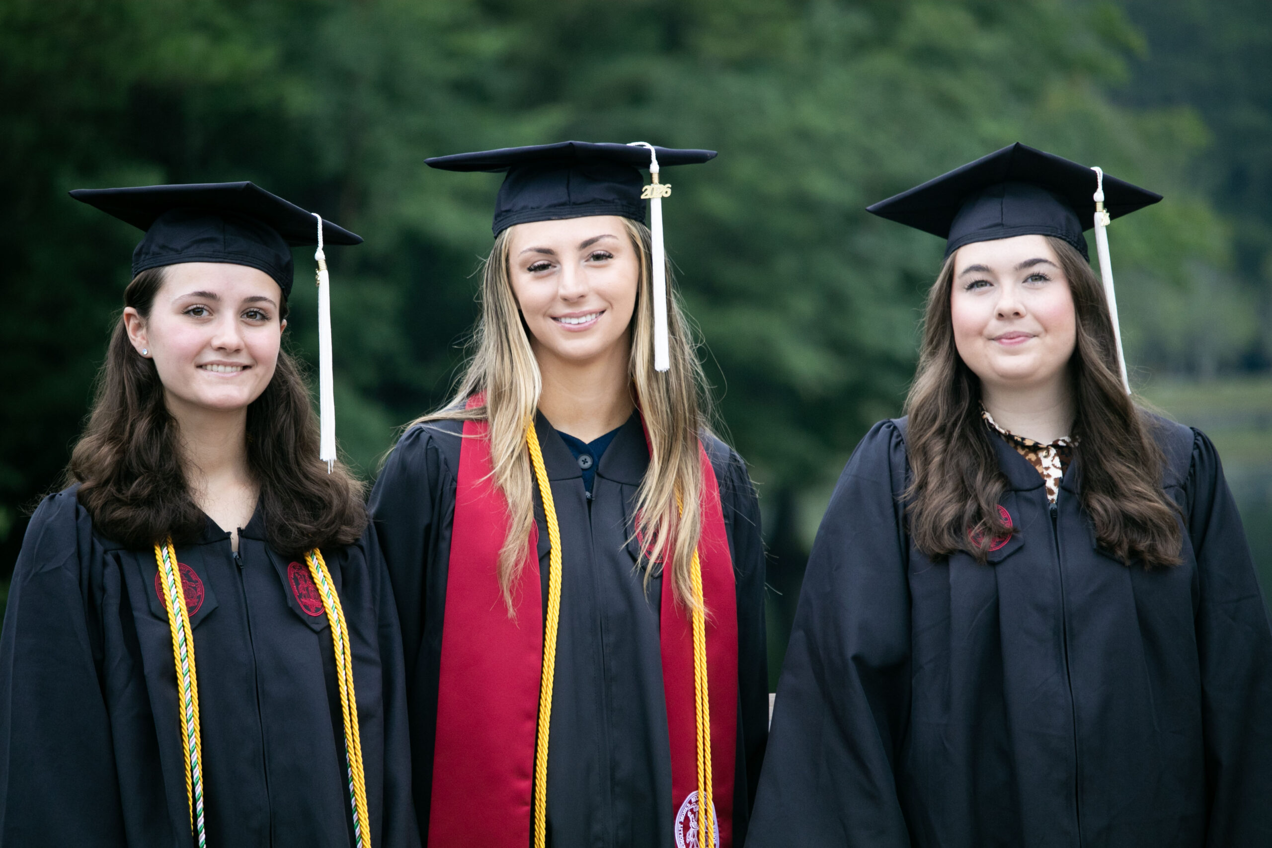 Three University of South Carolina graduates in caps and gowns who started their careers with the Lexington County Sheriff's Department